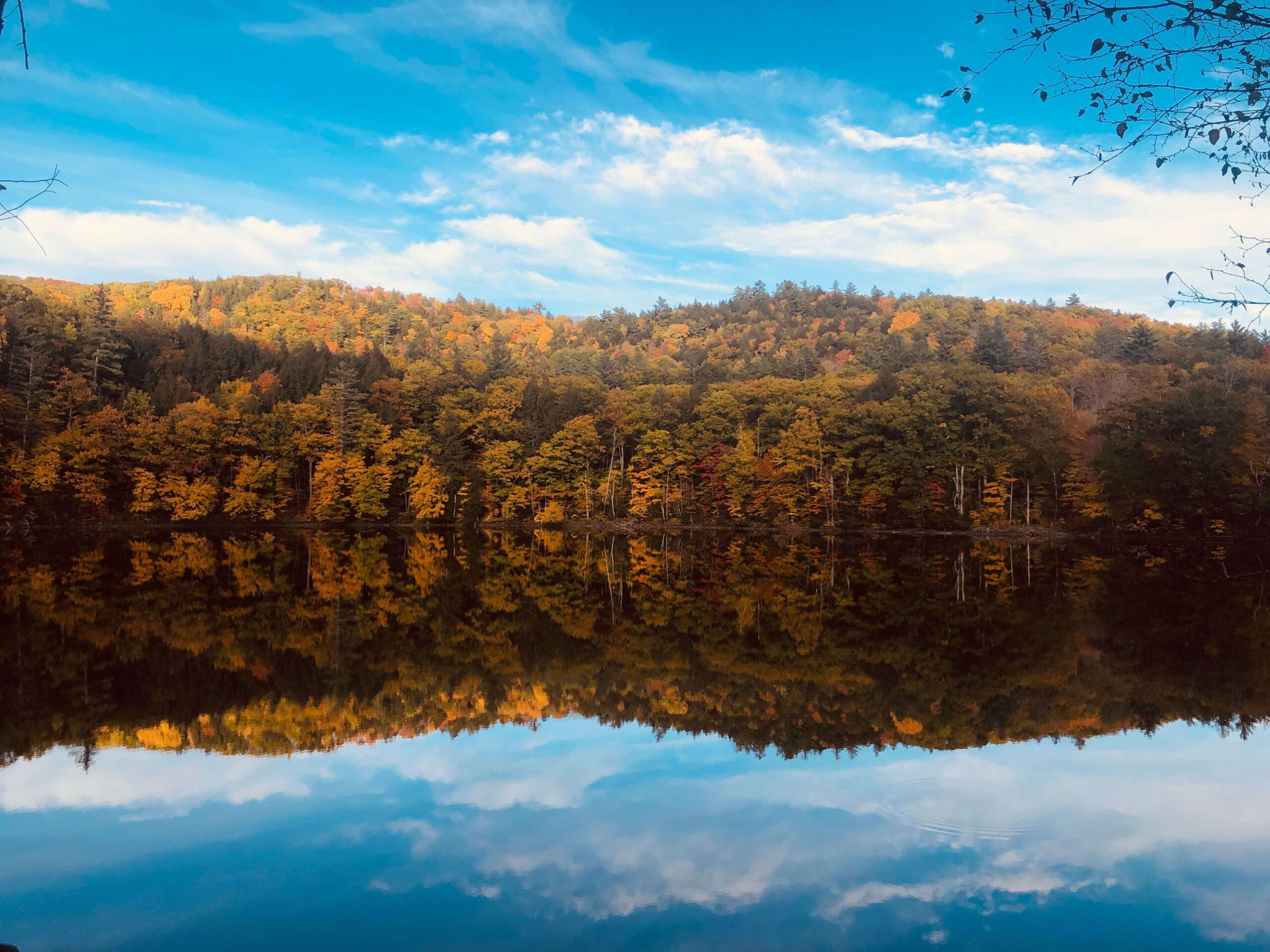 Beautiful autumn foliage reflected in a tranquil lake with a clear blue sky in Vermont