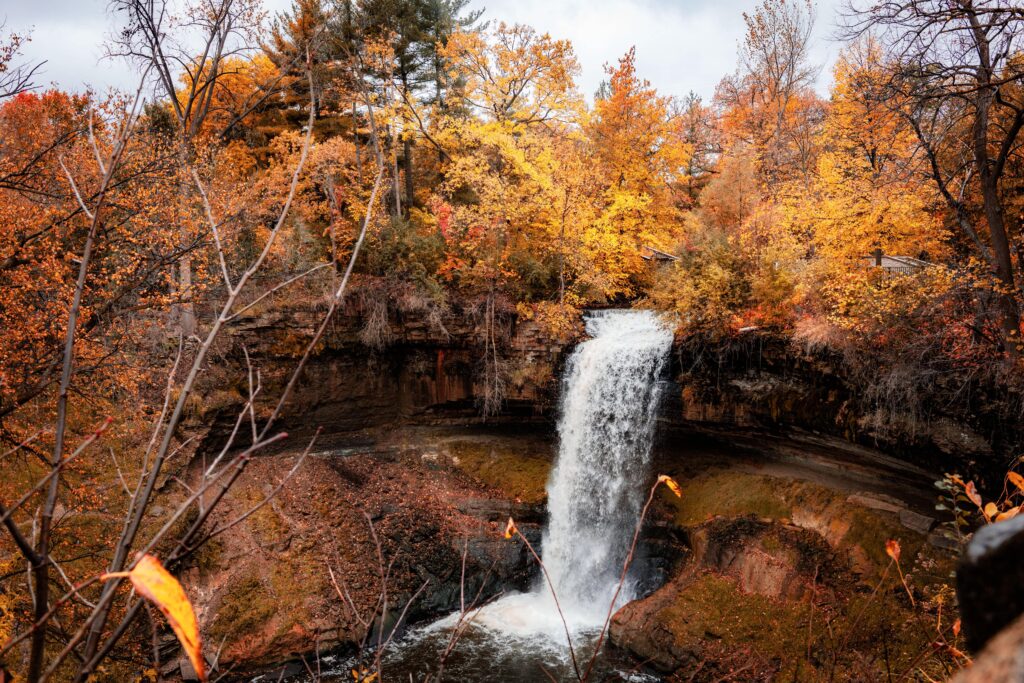 Explore the breathtaking autumn waterfall amidst vibrant fall foliage in Minneapolis, Minnesota