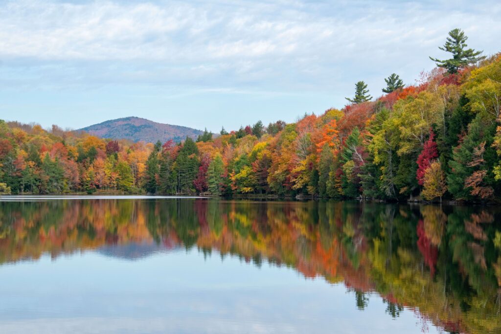 Gorgeous fall foliage reflecting in a tranquil Vermont lake, showcasing vibrant autumn colors